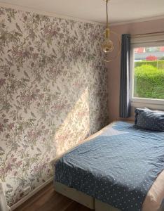 1 dormitorio con cama y papel pintado con motivos florales en comfortable apartment in a quiet area in the city center en Skien