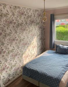 a bedroom with a bed and floral wallpaper at comfortable apartment in a quiet area in the city center in Skien