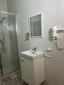 a white bathroom with a sink and a shower at Casa entre Rocas Setenil in Setenil