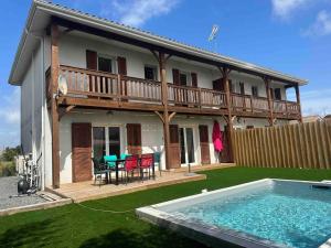 une maison avec une terrasse et une piscine dans l'établissement Maison 100m2 4 chambres avec piscine jardin paysage, à Gujan-Mestras