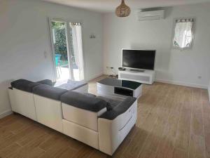un salon avec deux canapés et une télévision à écran plat dans l'établissement Maison 100m2 4 chambres avec piscine jardin paysage, à Gujan-Mestras