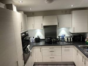 a kitchen with white cabinets and black appliances at Capewell Gibson House in Rotherham