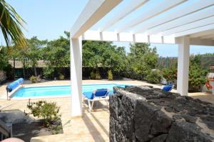 basen z krzesłami i białą pergolą w obiekcie Sun Grove Villas & Spa w mieście Playa Blanca