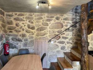 a room with a stone wall with a table and chairs at Petra's House Gerês in Geres