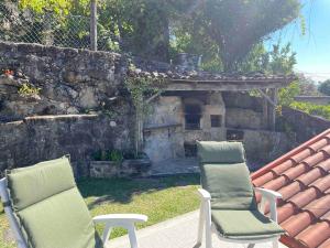 two chairs sitting on a patio with a stone fireplace at Petra's House Gerês in Geres