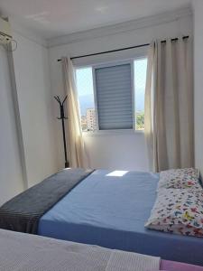 a bedroom with a bed in front of a window at Apto aconchegante beira mar com ar no quarto in Solemar