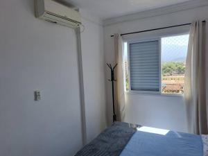 a bedroom with a blue bed and a window at Apto aconchegante beira mar com ar no quarto in Solemar