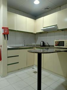 a kitchen with white cabinets and a granite counter top at The Sky Hosteller Dubai in Dubai