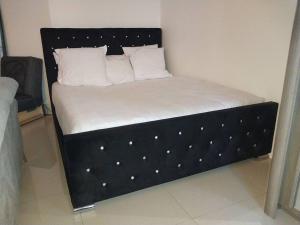 a bed with a black frame with white sheets and pillows at Peaceful home in Sevran