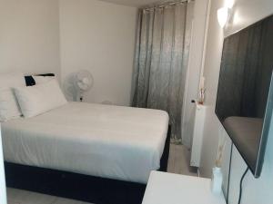 ein kleines Schlafzimmer mit einem weißen Bett und einem Fenster in der Unterkunft Peaceful home in Sevran