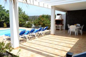 patio z krzesłami i stołem oraz basenem w obiekcie Sun Grove Villas & Spa w mieście Playa Blanca