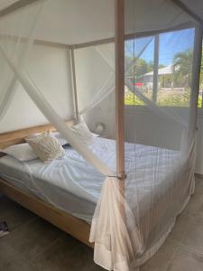 a bedroom with a canopy bed with a window at Villa Tropic' Al. Piscine privée. Cuve à eau in Saint-François