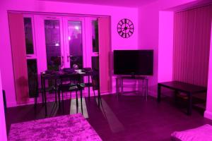 a living room with a pink room with a tv at Modern house in City Centre with private parking and gated property in Birmingham