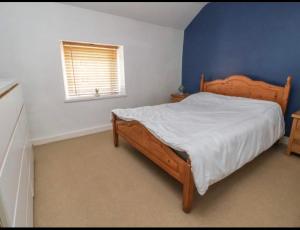 a bedroom with a wooden bed with a blue wall at Coastal Village Cottage in Talacre