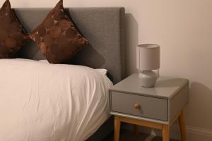 a bed with a night stand with a lamp on it at Modern house in City Centre with private parking and gated property in Birmingham