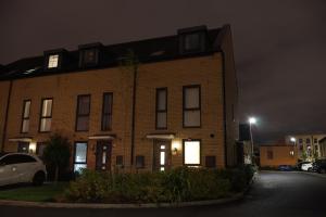 a brick house at night with a car parked in front at Modern house in City Centre with private parking and gated property in Birmingham