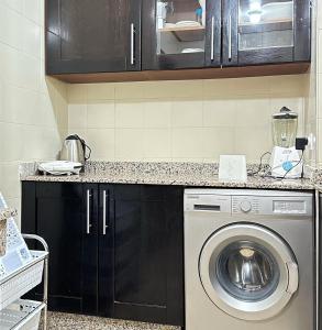 a washing machine in a kitchen with black cabinets at Best Apartment in Marina Agadir in Agadir