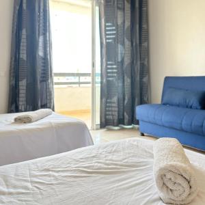 a bedroom with two beds and a blue couch at Best Apartment in Marina Agadir in Agadir
