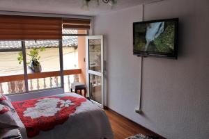 1 dormitorio con 1 cama y TV en la pared en Chaska Hotel, en Otavalo