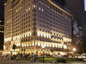 un grand bâtiment la nuit avec des personnes devant lui dans l'établissement The Plaza, à New York