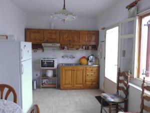cocina con armarios de madera y nevera blanca en Δυάρι Διαμέρισμα με μπαλκόνι στην Κριτσά, en Kritsá