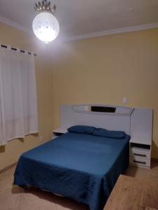 Un dormitorio con una cama azul y una lámpara de araña. en Espaço para Festa e Pousada Alex Ávila, en Diamantina
