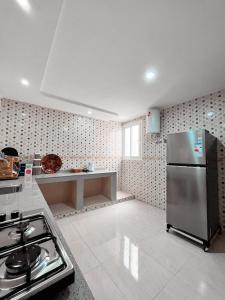 eine Küche mit einem Kühlschrank aus Edelstahl und einem Herd in der Unterkunft RÉSIDENCE SNIYA in Ad-Dakhla