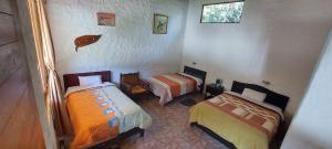 1 dormitorio con 2 camas y un pez en la pared en Mindo Loma bird lodge, en Mindo