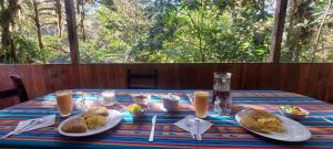 una mesa con platos de comida y vasos de zumo de naranja en Mindo Loma bird lodge, en Mindo