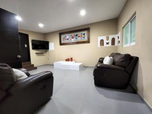 een woonkamer met 2 leren stoelen en een televisie bij Quinta las huertas in Tlajomulco de Zúñiga