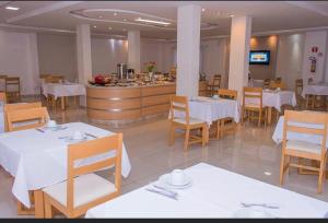 a restaurant with white tables and chairs and a counter at FLORENÇA PALACE HOTEL in Lucas do Rio Verde