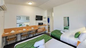 a hotel room with two beds and a desk at CBD GI Motel in Glen Innes