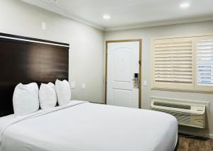 1 dormitorio con 1 cama blanca grande con almohadas blancas en Rodeway Inn Lemon Grove San Diego East, en Lemon Grove