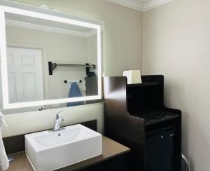 ein Badezimmer mit einem weißen Waschbecken und einem Spiegel in der Unterkunft Rodeway Inn Lemon Grove San Diego East in Lemon Grove