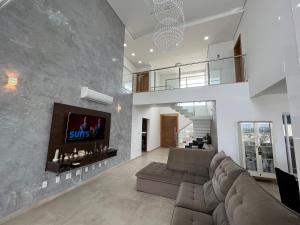 a living room with a couch and a tv on a wall at Quartos privativos - Casa de alto padrão in Guaratinguetá