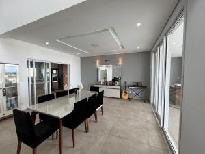 a dining room with a glass table and black chairs at Quartos privativos - Casa de alto padrão in Guaratinguetá