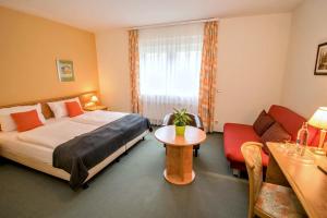 a bedroom with a bed and a table and a couch at Landhotel Ringelsteiner Mühle in Moselkern