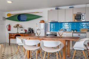 a kitchen with a wooden table and white chairs at Sea House in São Vicente