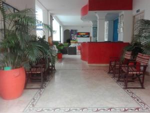 un vestíbulo con sillas y un mostrador rojo en un edificio en Hotel Bucaros, en Espinal