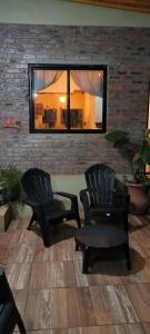 duas cadeiras e uma mesa em frente a uma parede de tijolos em Casa de Toto 3 habitaciones em Puerto Iguazú