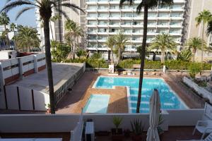 een zwembad met palmbomen en een groot gebouw bij Tropical Views - Paya del Inglés in Maspalomas