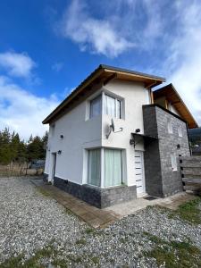 Una casa blanca con una ventana en el costado. en ALBANTA Lago Puelo en Lago Puelo