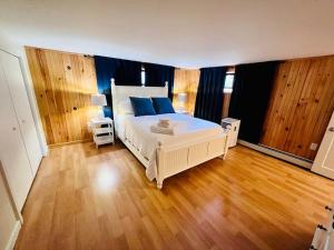 a bedroom with a large white bed and wooden floors at Historic Corner Apartment with patio & off street parking in Portland