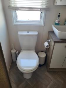 uma casa de banho com um WC, um lavatório e uma janela em Your Retreat Too em Camber