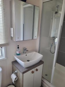 uma casa de banho com um lavatório branco e um chuveiro em Your Retreat Too em Camber