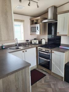 uma cozinha com armários brancos e um forno com placa de fogão em Your Retreat Too em Camber