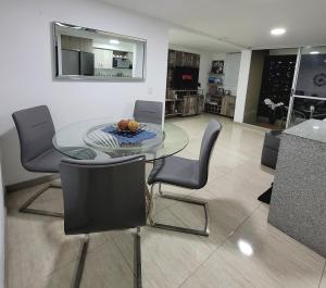 une salle à manger avec une table et des chaises en verre dans l'établissement Modern 2/2 Apartment in Sabaneta with City View, à Sabaneta