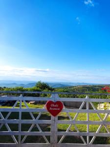 a sign on a fence with a valley in the background at Chalé Formoso - Chalé Romântico com Hidromassagem in Serra de São Bento
