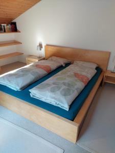ein Schlafzimmer mit einem Bett mit einem Holzrahmen in der Unterkunft Moderne attraktive Dachwohnung für max. 6 Personen in ruhiger Umgebung in Flims