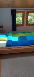 ein Bett mit blauer und grüner Bettwäsche und zwei Fenstern in der Unterkunft Moderne attraktive Dachwohnung für max. 6 Personen in ruhiger Umgebung in Flims